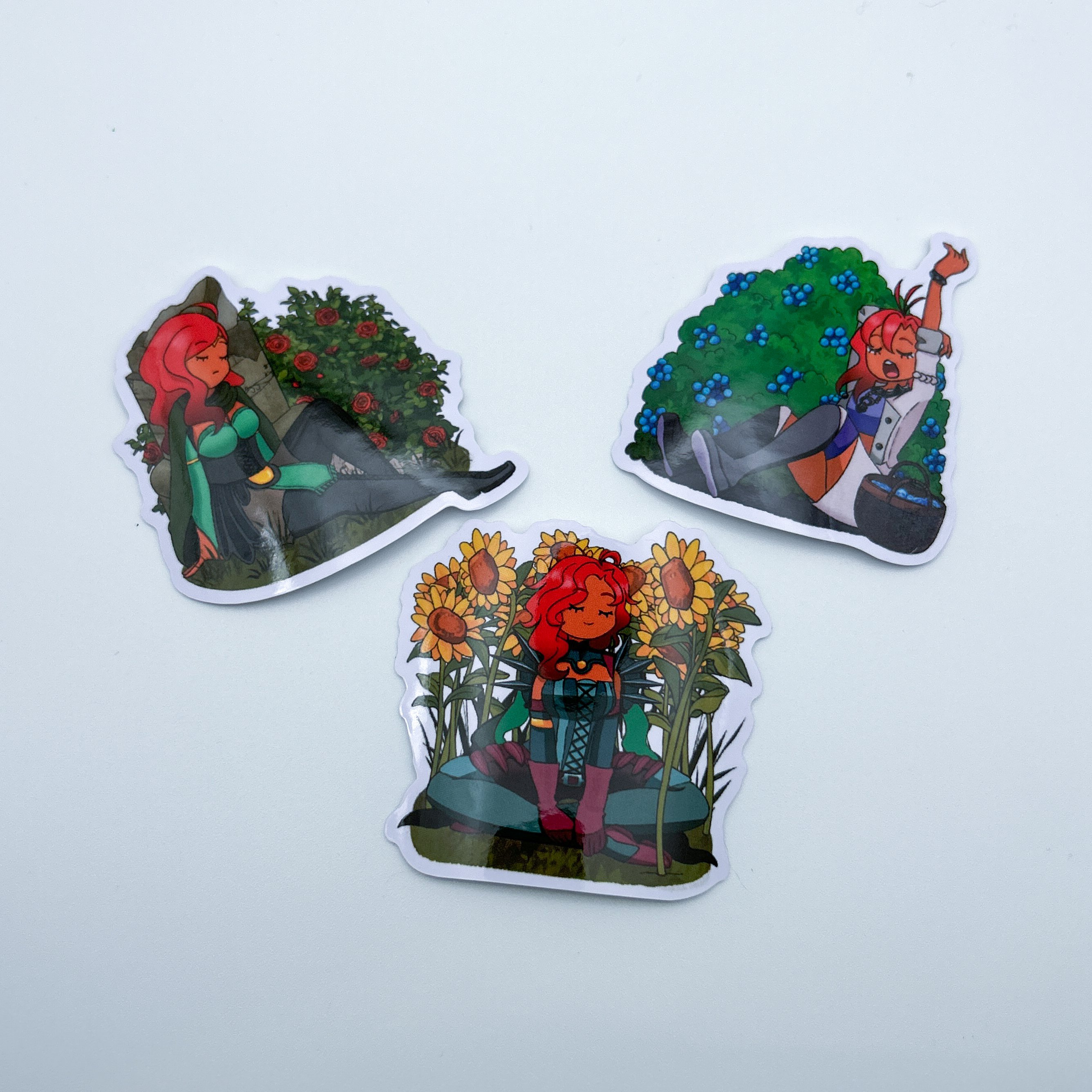 Hapi Zine Sticker Set - A set of 3 stickers depicting Hapi from Fire Emblem: 3 Houses. Each Hapi is from a different timeline in the games (one being pre-timeskip, post-timeskip, and from Fire Emblem Warriors: Three Hopes). Each Hapi is taking a nap among different coloured flowers or plants. 